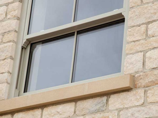close up of brickwork and green upvc sliding sash window
